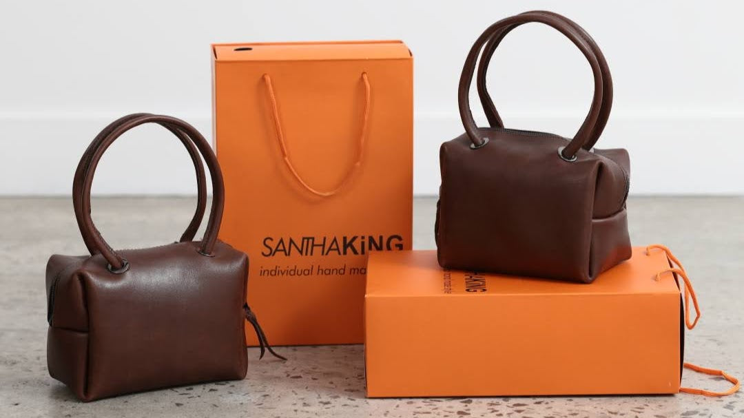 Stand out with this small but mighty trunk tote in brown Australian leather with tubular handles.