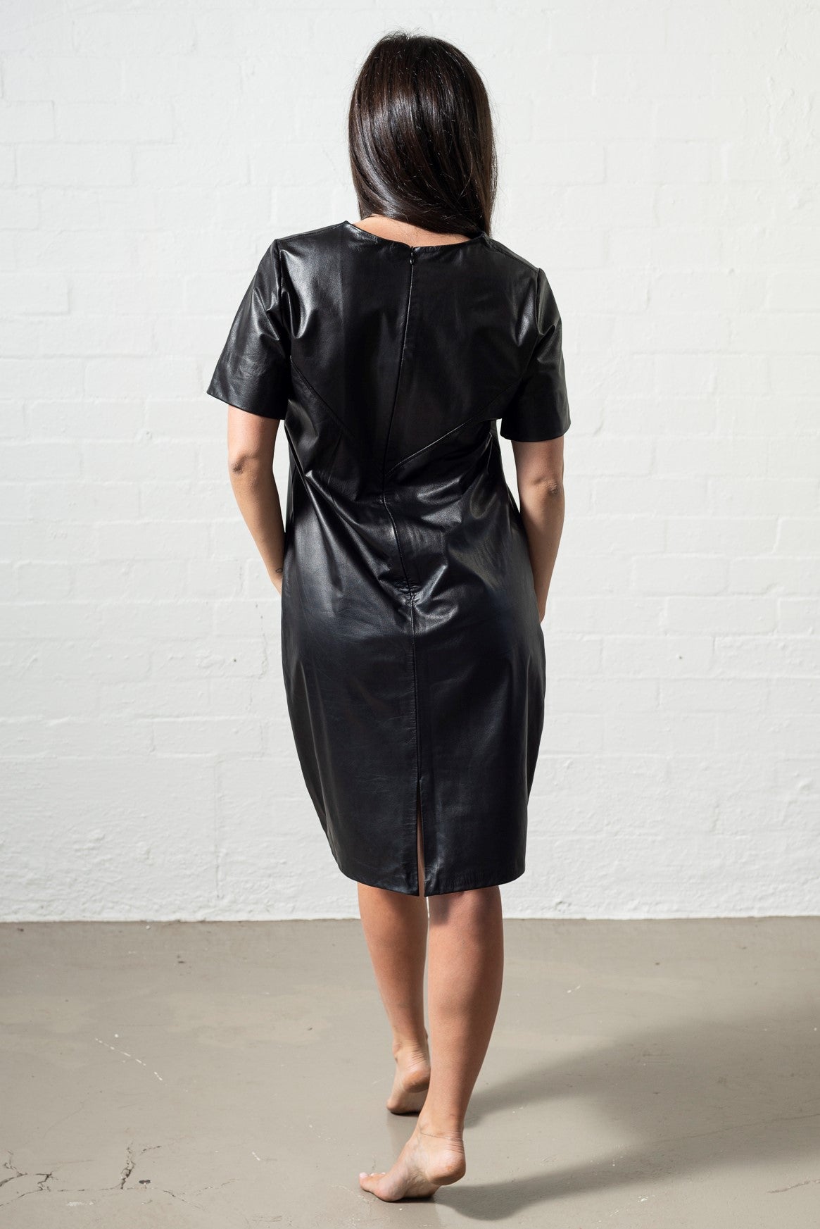 This little black leather dress has subtle angled detailing, a centre back zip and split