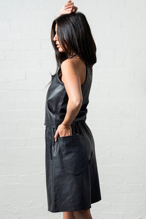 Side view of black leather tank top paired with culottes and an oversized pocket